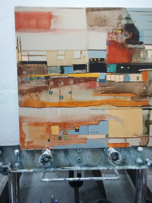 Abstract painting in orange, rust and pale blue on an easel